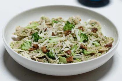white bowl filled with pesto pasta and walnuts