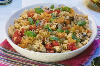 white bowl filled with tomato and chicken pasta salad
