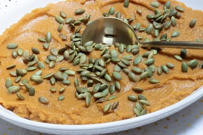 large bowl of sweet potato and butternut mash topped with pumpkin seeds