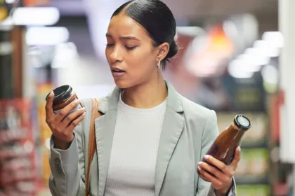 women looking at 2 jar labels in the grocery store