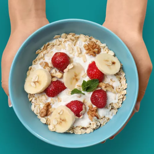 blue bowl of oatmeal with berries and bananas.