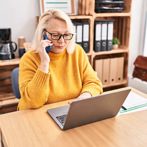 woman on phone while looking at computer