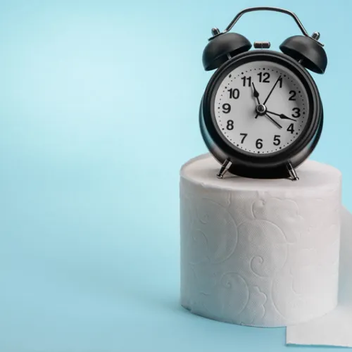alarm clock sitting on a roll of toilet papper