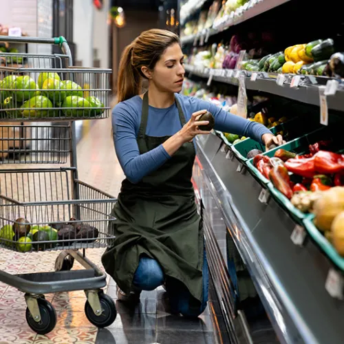 Grocery store employee restocking produce