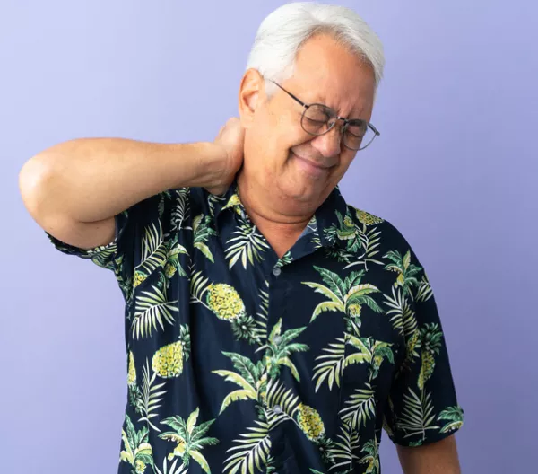 Older man holding the back of his neck and wincing