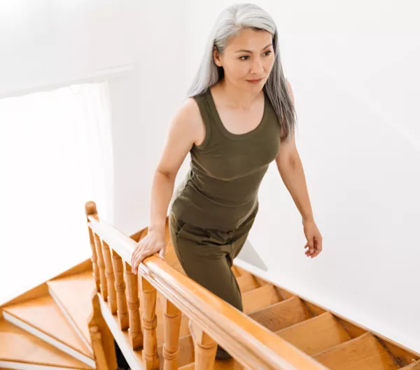 older woman climbing wooden stairs