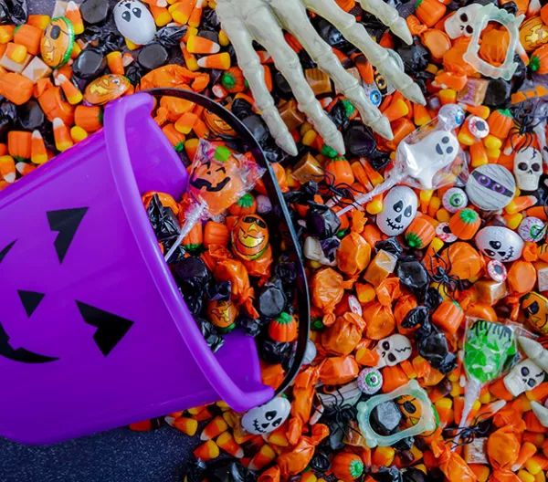 Halloween candy spilling out of purple pumpkin bucket