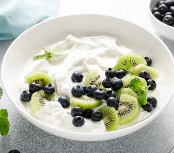 bowl of yogurt with blue berries and kiwis