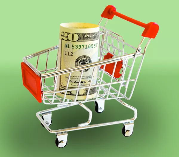 roll of cash in a shopping cart on green background