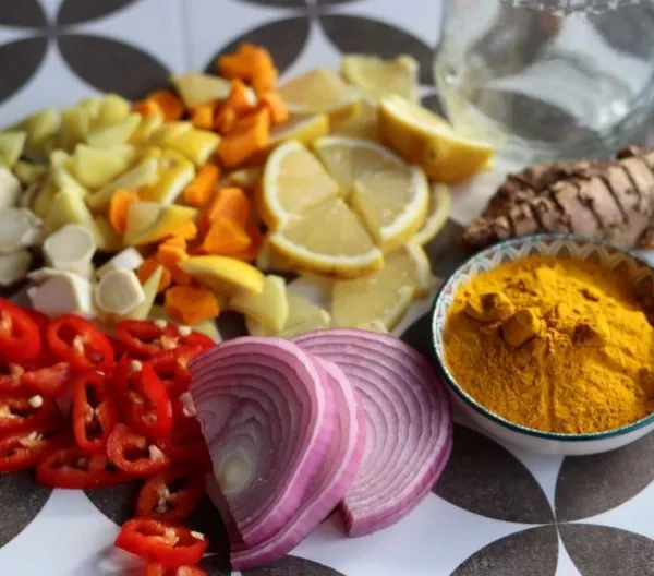 Fire cider chopped ingredients on grey tiled background. Top view photo of turmeric, ginger, pepper, garlic, onion and lemon.