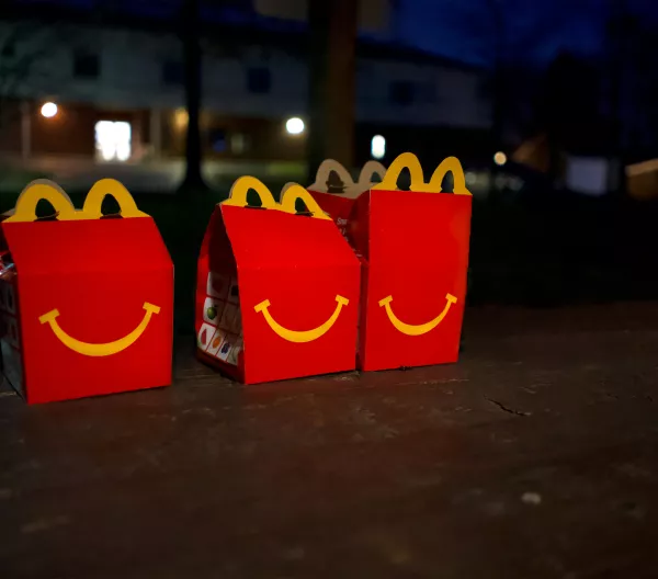 Three unopened Happy Meal boxes sitting on pavement