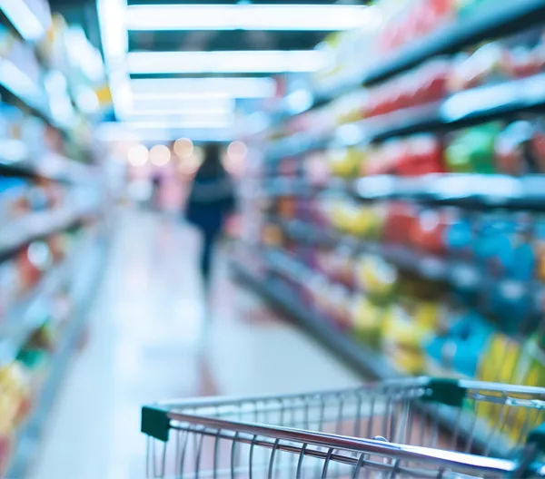 grocery cart in focus in the foreground with grocery store shelves out of focus in the background