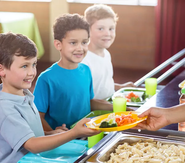 Woman serving food to schoolchildren