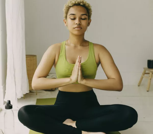 woman sitting crisscross with prayer hands as a yoga pose 