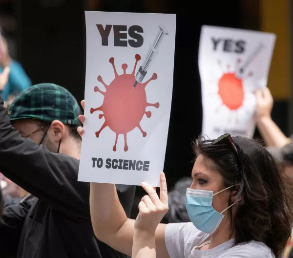 A group of people holding pro-science signs and wearing masks