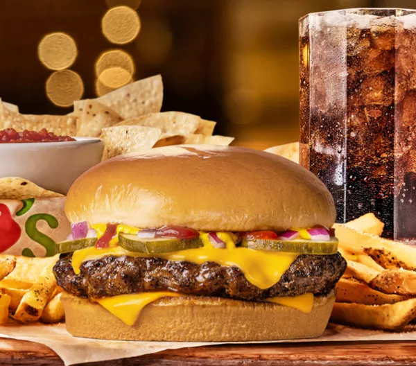 Chilis Big QP burger surrounded by fries with chips and salsa and large soda