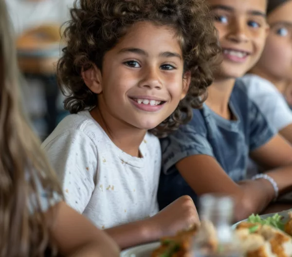 kids sitting at a table with food in front of them