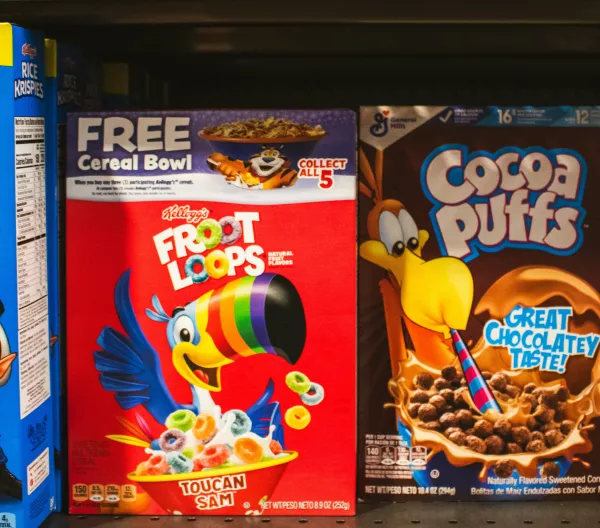 A supermarket shelf displaying boxes of brightly colored breakfast cereals.