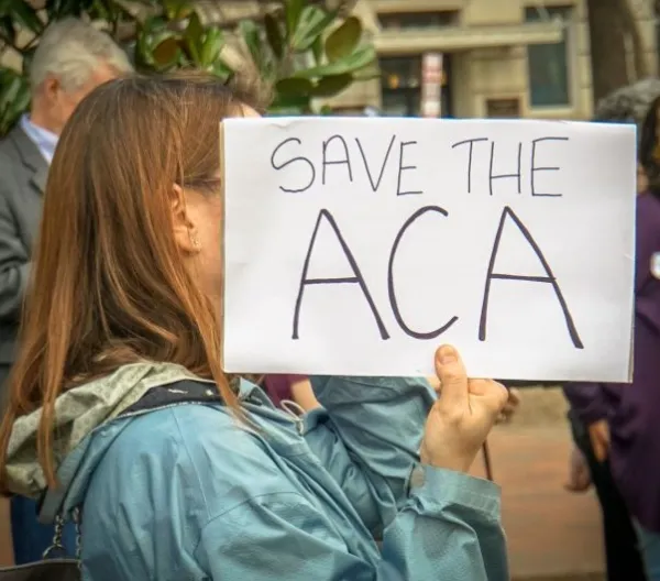 Rally in Support of the Affordable Care Act, at The White House, Washington, DC USA, carrying a sign that reads "SAVE THE ACA"