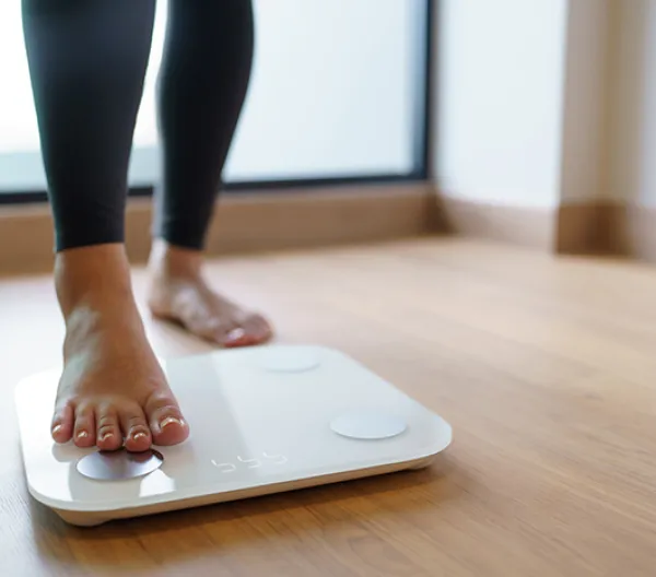 person stepping on a scale on wood floor