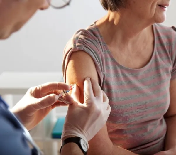 An older woman receives a vaccination shot in a doctor's office