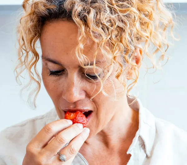 Woman taking a bite of a red berry