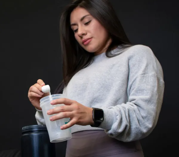 woman scooping powder into clear cup