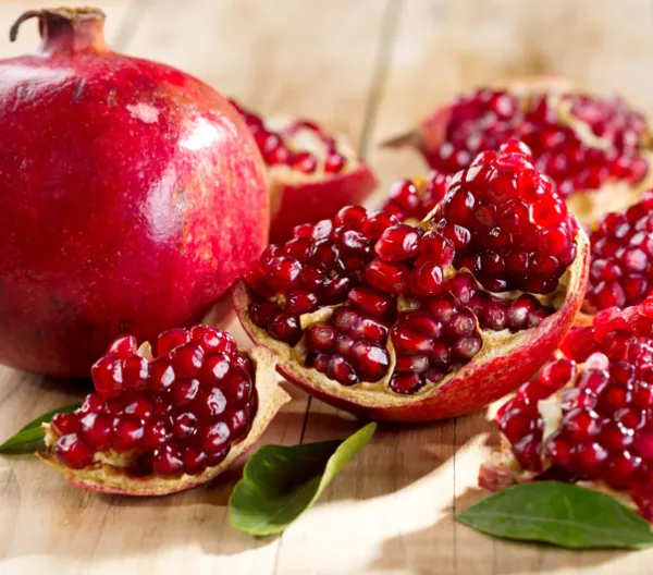 1 whole pomegranate and one split up laying next to each other