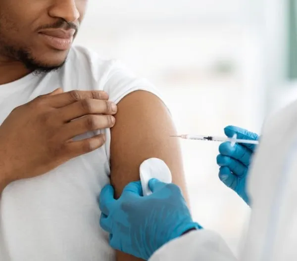 A medical professional administers a Covid vaccine to a Black man
