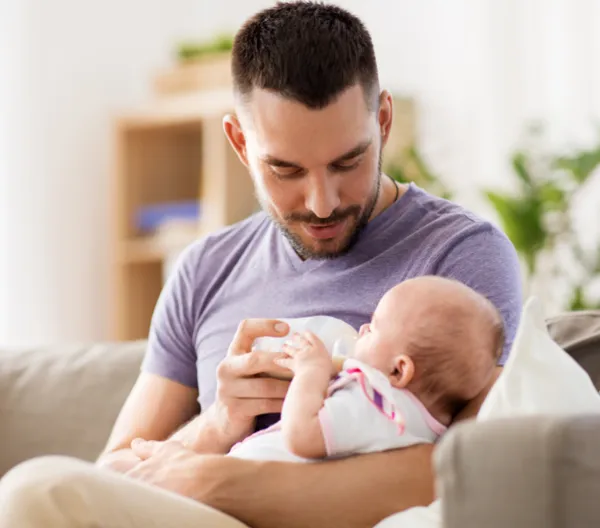 man bottle feeding a baby