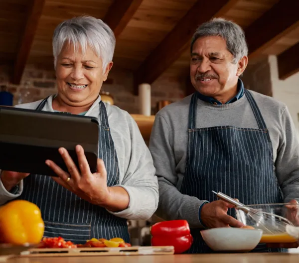 couple looking at an iPad and cooking in the kitchen