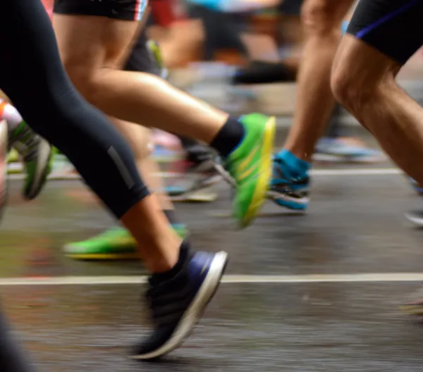 legs and feet of runners passing on a road