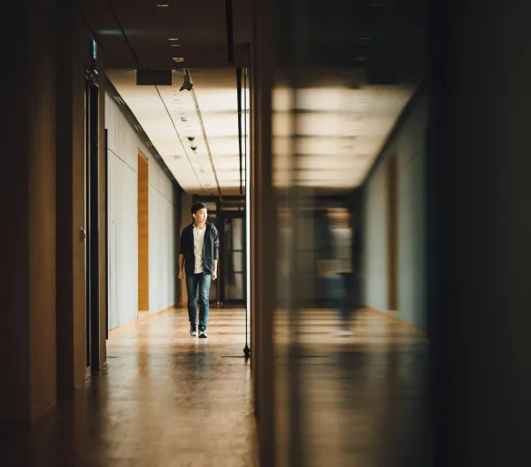 An adolescent boy walking alone down a school hallway