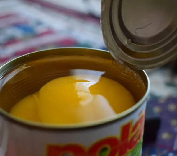 An open can of peaches in heavy syrup. 