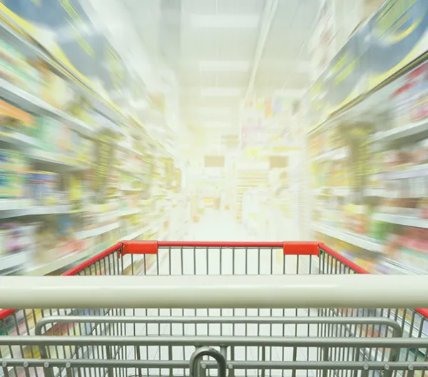grocery cart in focus in the foreground with grocery store shelves out of focus in the background