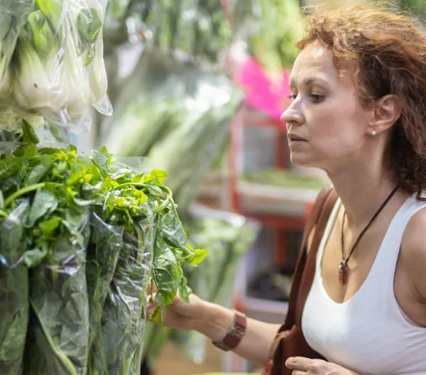 woman choosing a bunch of leafy greens in grocery store