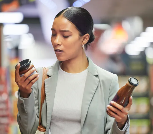women looking at 2 jar labels in the grocery store