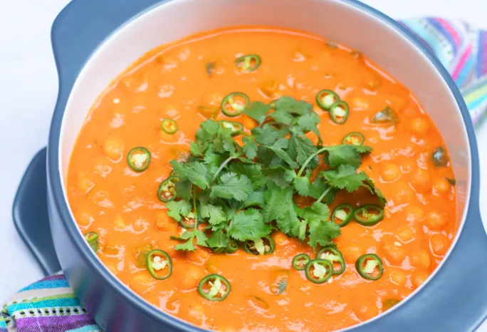 large blue pot of paprika chickpeas with green garnishes