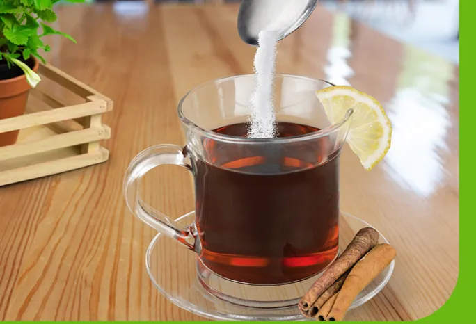 clear mug holding tea pouring sugar into