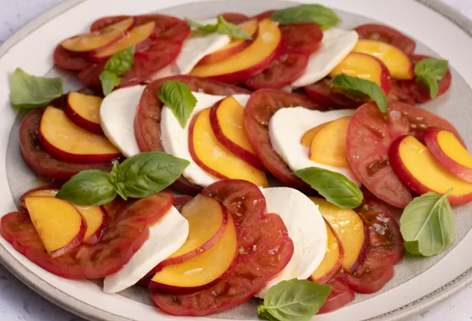 Plate with tomato, mozzarella, nectarine slices and basil