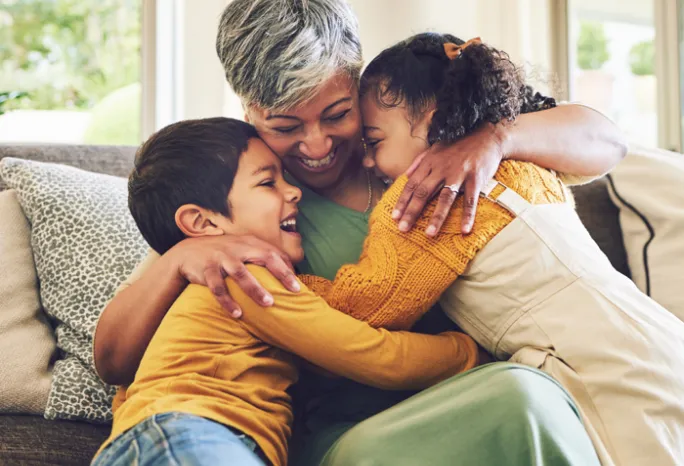 older woman hugging 2 younger children