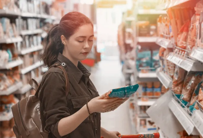 a woman reading a food package label in a grocery store