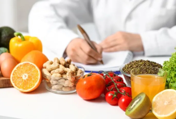 Young female nutritionist with healthy food writing diet plan in office, closeup