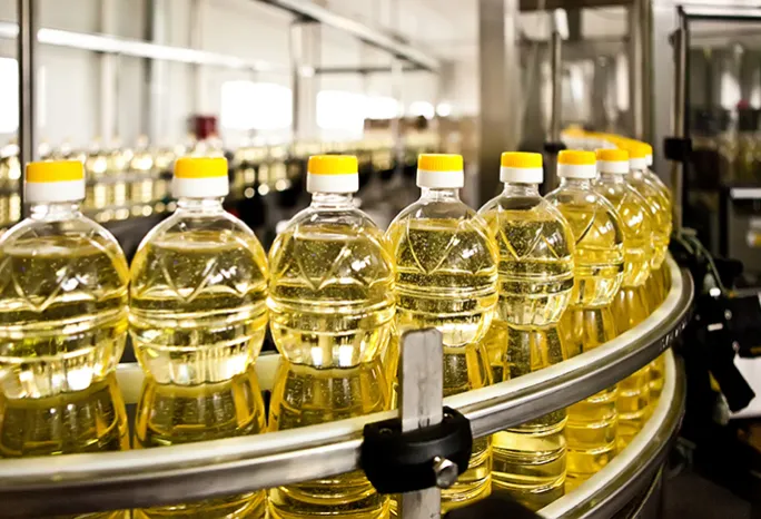 line of clear bottles of oil in a factory