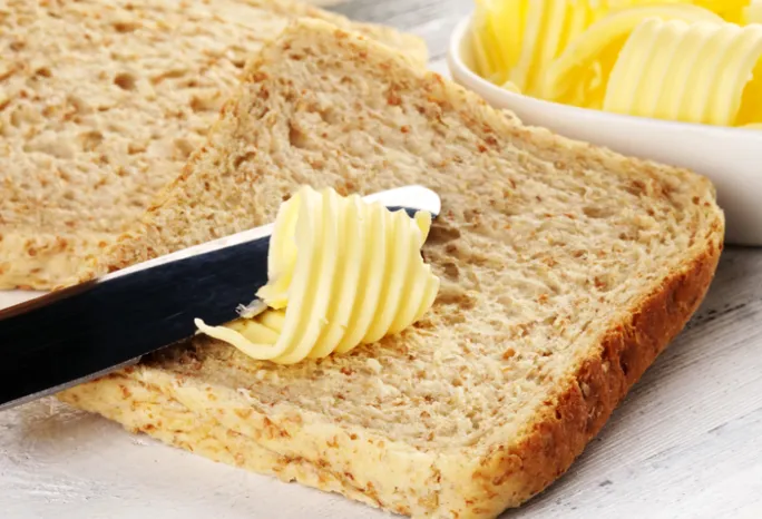 knife spreading butter on slice of bread