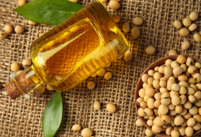 glass bottle full of seed oil on burlap background with seeds sprinkled around