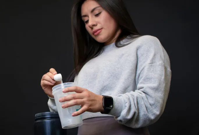 woman scooping powder into clear cup