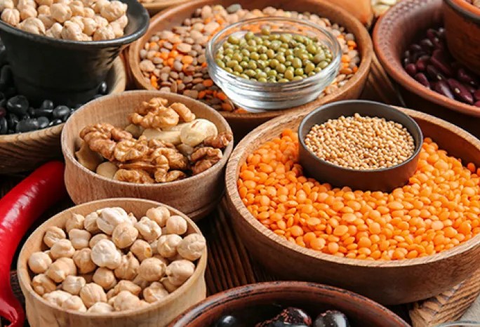 several wooden bowls fille with all different lentils and legumes