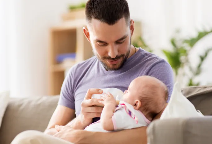 man bottle feeding a baby