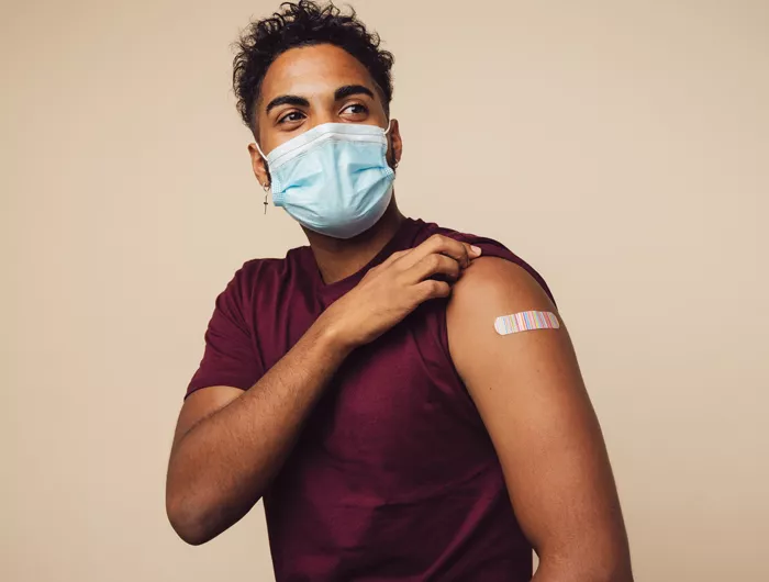a young man showing the site of his covid-19 vaccine